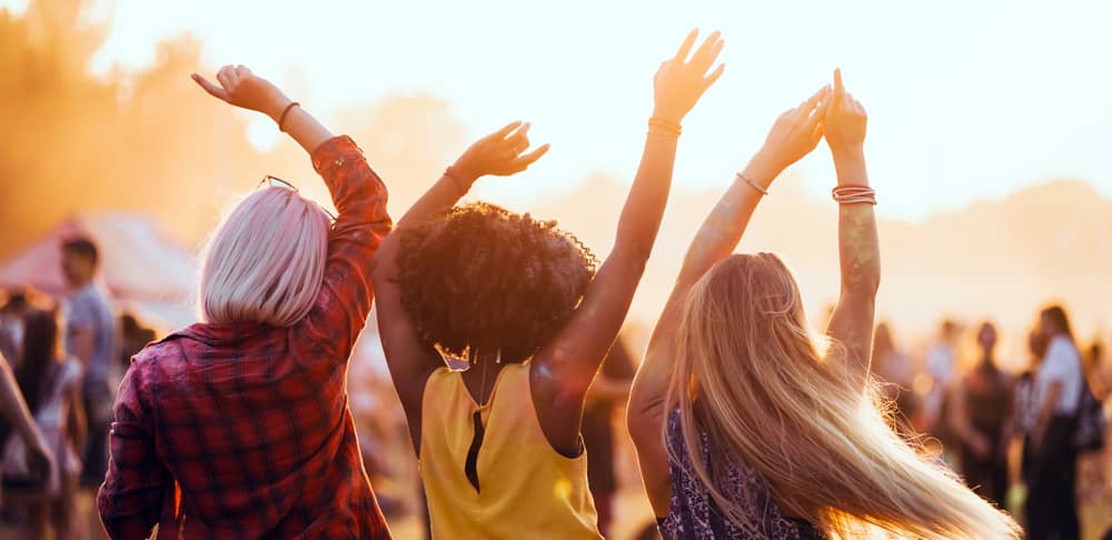 Freundinnen feiern auf einem Festival im sommerlichen Ambiente.