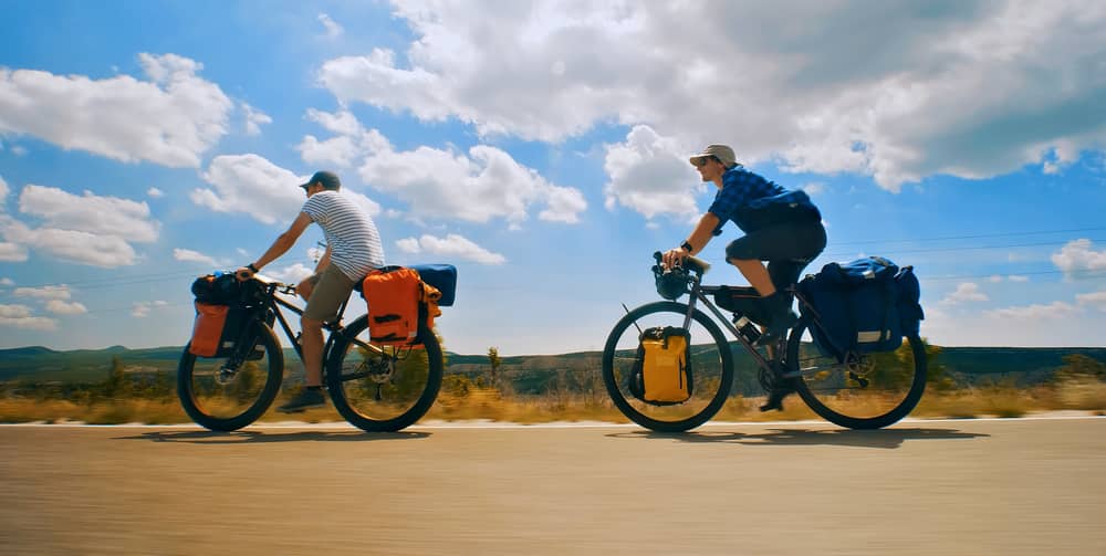 Zwei Radfahrer auf einer Landstraße mit Equipment für ihre Fahrradtour-