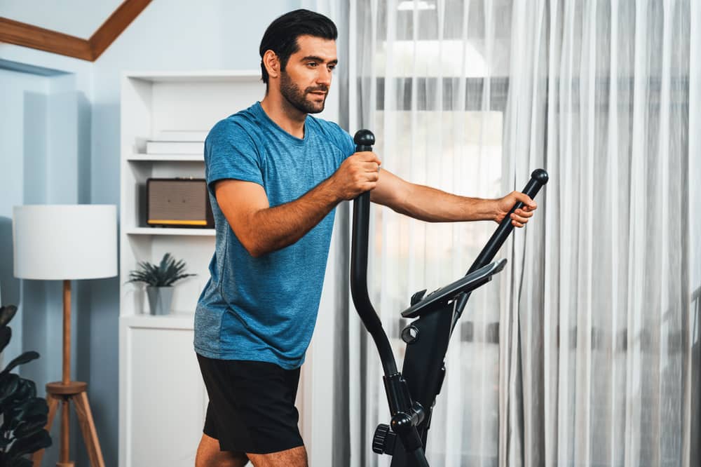 Ein Mann trainiert zuhause auf einem Ergometer.