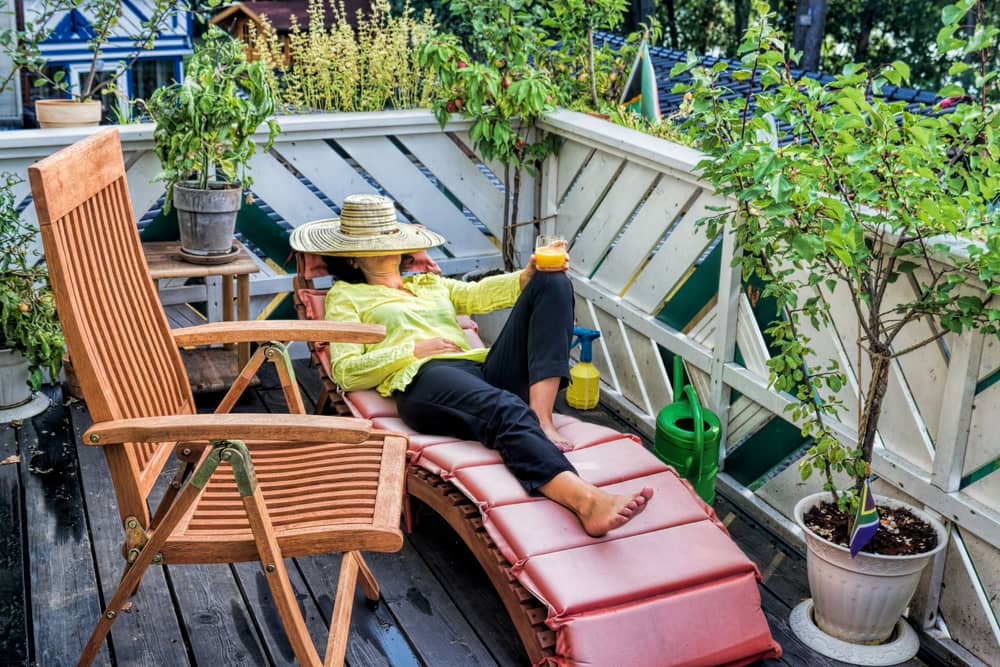 Eine Frau entspannt auf dem Balkon im Liegestuhl