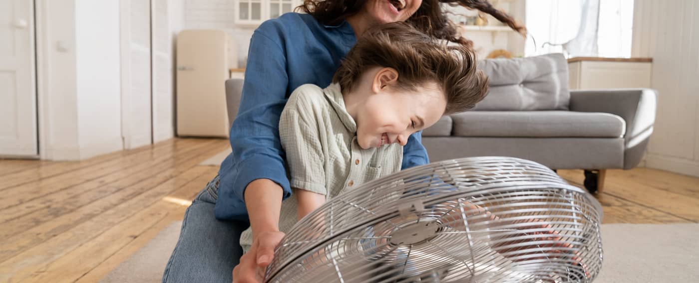 Mutter und Kind vor einem Ventilator.