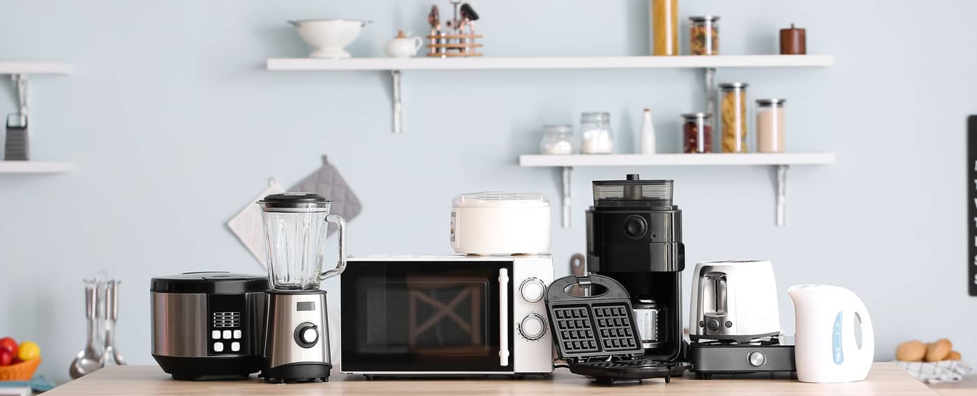 Eine moderne Küche mit vielen Küchengeräten wie einem Toaster, einem Smoothie-Maker und einem Waffeleisen auf der Arbeitsplatte.