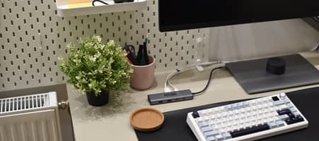 Ein Schreibtisch mit Bildschirm, Tastatur und Laptop. Alles ist ordentlich mit Kabeln verbunden. Dahinter sind kleine Gegenstände an einer Lochwand befestigt oder liegen in eingehängten Schubladen.