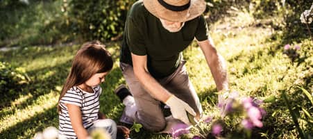 Ein kleines Mädchen hilft ihrem Großvater bei der Gartenpflege