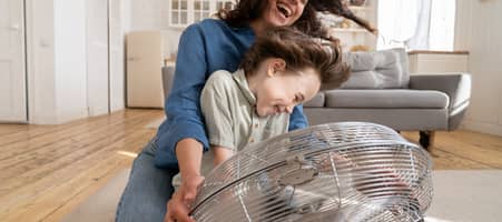 Mutter und Kind vor einem Ventilator.
