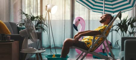 Ein Mann entspannt mit Fußbad und Sonnenschirm in der eigenen Wohnung